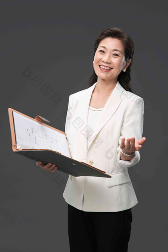 拿着户型图册做出邀请手势的成熟商务女士