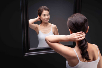 对着镜子<strong>梳头</strong>发的中年女人身体关注写实影相