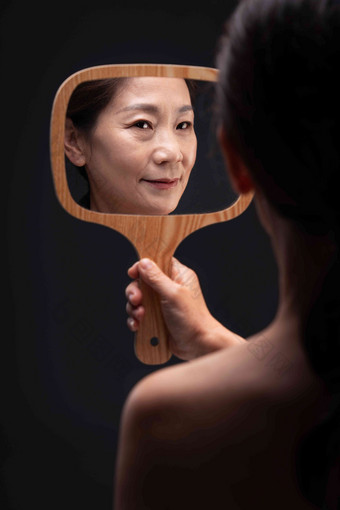 拿着镜子照的中年女人皮肤高清摄影图