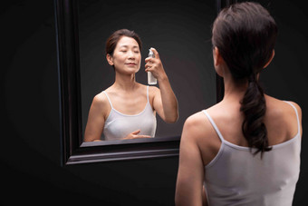 优雅的中年女人对着镜子喷爽肤水舒适高端图片