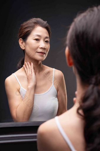 优雅的中年女人对着镜子做颈部护理放松清晰素材