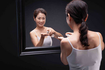 优雅的中年女人对着镜子喷爽肤水微笑高端影相