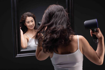 <strong>中年女人</strong>对着镜子用吹风机吹头发享乐高质量影相
