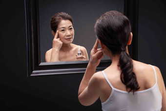 优雅的中年女人对着镜子涂抹爽肤水中年人高端镜头