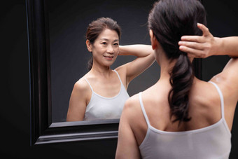 对着镜子调整发型的中年女士舒适高端镜头