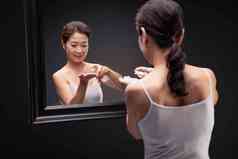 优雅的中年女人对着镜子喷爽肤水