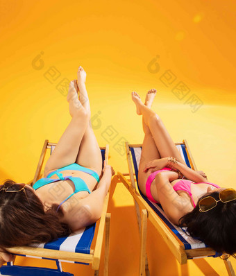 比基尼闺蜜坐在沙滩上日光浴优雅氛围照片