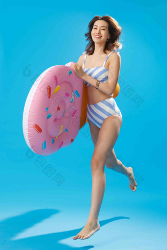 抱着冰淇淋形状的浮排跳跃的泳装美女