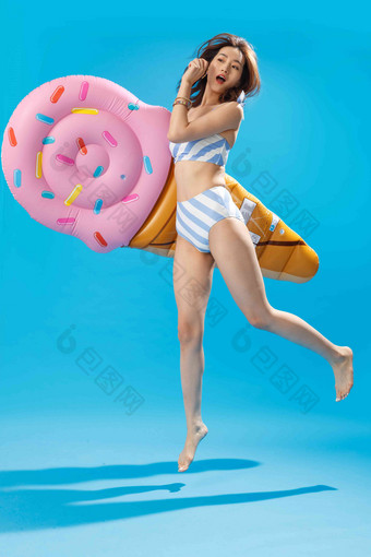抱着冰淇淋形状的浮排跳跃的泳装美女