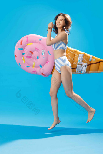 抱着冰淇淋形状的浮排跳跃的比基尼美女