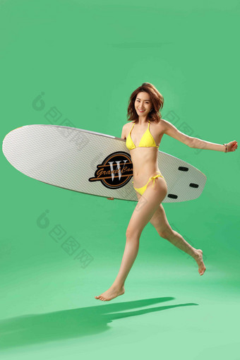 快乐的青年女人抱着冲浪板一个人写实图片