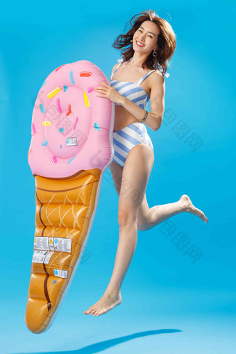 拿着冰淇淋形状的浮排跳跃的比基尼美女微笑写实相片
