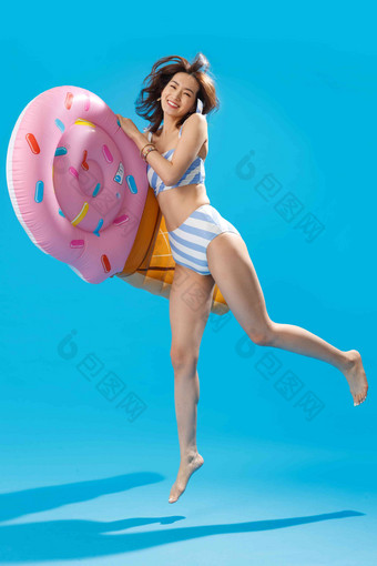 抱着冰淇淋形状的浮排跳跃的比基尼美女清新清晰拍摄