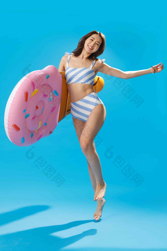 抱着冰淇淋形状的浮排跳跃的比基尼美女充气玩具清晰镜头