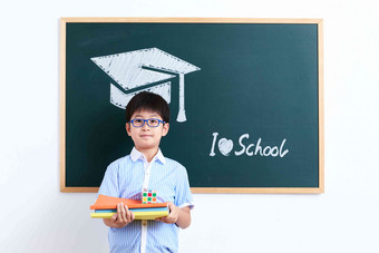 小学男生站在黑板前教科书写实素材