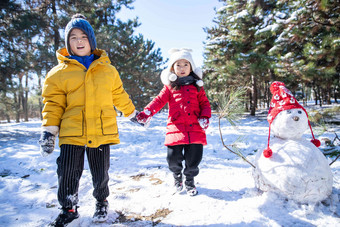快乐儿童和雪人手牵手写实摄影图