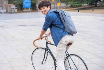 大学生在校园里骑自行车大学青年氛围场景
