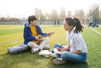 青年大学生在校园里弹奏吉他休闲相片