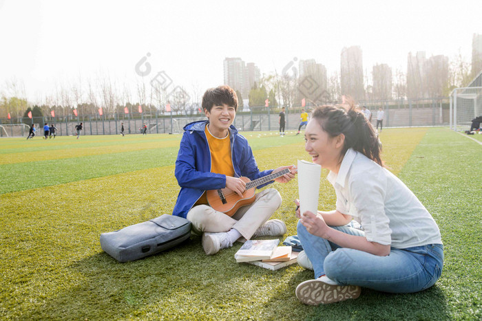 青年大学生在校园里弹奏吉他微笑高端摄影图