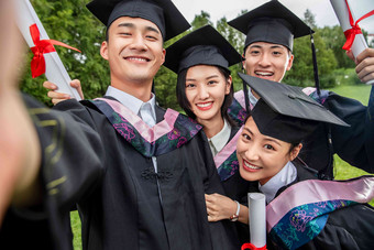 四个身穿学士服的大学生扶着镜头一起自拍微笑的高端图片