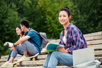 快乐的大学生坐在台阶上学习笔记本电脑氛围素材