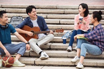 年轻的大学生坐在台阶上弹吉他友谊高清摄影