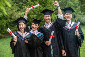 户外兴奋的穿着学士服的大学生们庆祝氛围影相