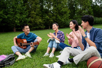 快乐的大学生在草地上弹吉他唱歌弹奏氛围影相
