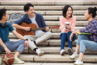 年轻的大学生坐在台阶上弹吉他