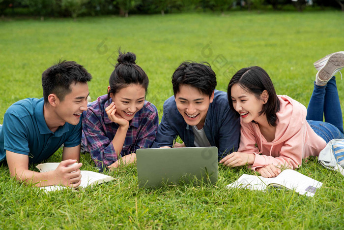 快乐的大学生趴在草地上学习清新氛围图片