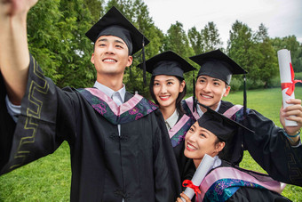 四个身穿学士服的大学生扶着镜头一起自拍拿着清晰拍摄