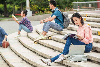 快乐的大学生坐在台阶上学习三个人写实素材