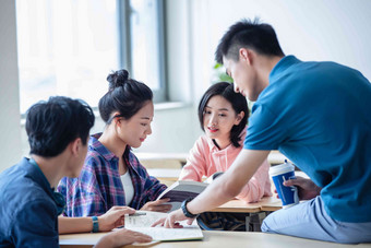 大学生在教室内交流学习课桌高清照片