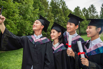 四个身<strong>穿学士服</strong>的大学生用手机自拍