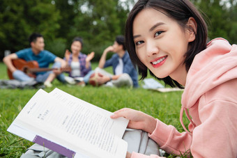 大学生在草地上享受课余时间<strong>拿着</strong>相片