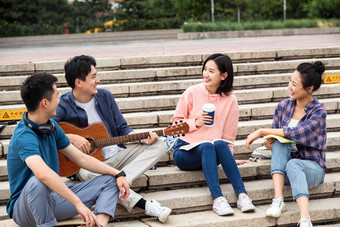 年轻的大学生坐在台阶上闲聊