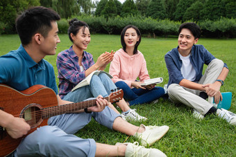 快乐的大学生在草地上弹吉他唱歌唱歌高端照片