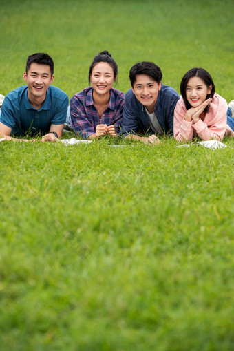 快乐的大学生趴在草地上友谊摄影图