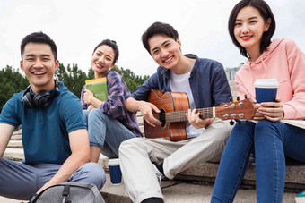 年轻的大学生坐在台阶上弹吉他中国人氛围相片