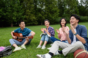 快乐的大学生在草地上弹吉他唱歌沟通照片