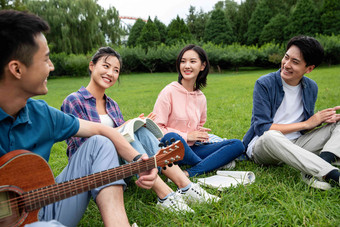 快乐的大学生在草地上弹吉他唱歌弹奏写实摄影