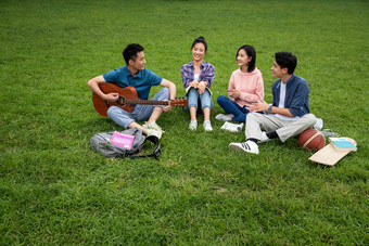 快乐的大学生在草地上弹吉他唱歌四个人高清摄影