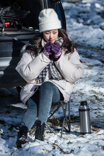 坐在汽车旁喝热水的青年女人人场景