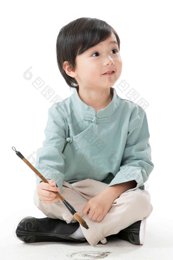 小男孩盘腿坐着拿毛笔写字