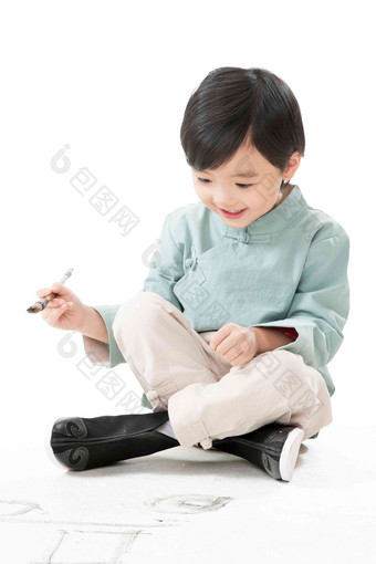 小男孩盘腿坐着拿<strong>毛笔</strong>写字欢乐清晰照片