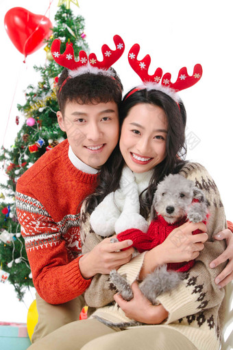 抱着宠物狗的青年情侣过圣诞节