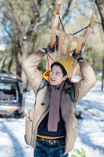 雪地上步行举着雪橇的青年男人放松高清素材