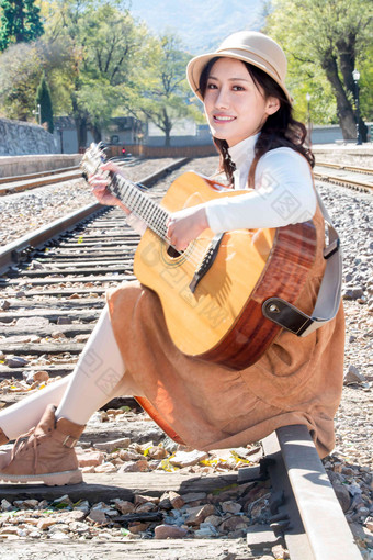 青年女人坐在铁路边<strong>弹吉他</strong>