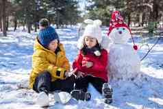 坐在雪地上玩耍的儿童和雪人
