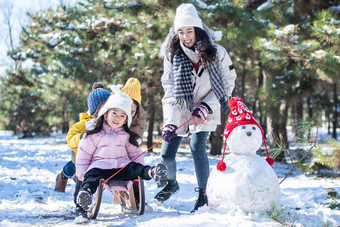 在雪地上玩雪橇的一家人